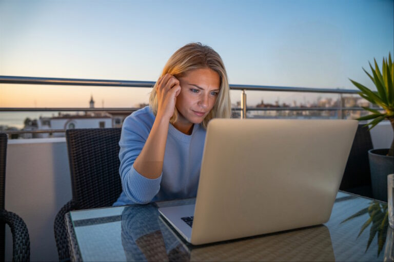 Eine Frau sitzt auf der Terrasse am Laptop mit WLAN Empfang.